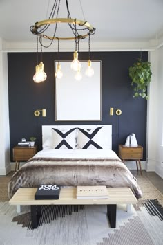 a bedroom with a large bed and two lamps hanging from the ceiling over it's headboard