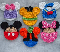 crocheted mickey mouse and minnie mouse head appliques on a gray surface