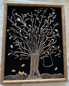 an embroidered tree with leaves and birds in the center is framed on a black background