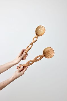 two wooden spoons being held by one hand and the other is spinning them on top of each other