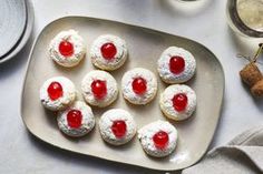 small pastries with cherry toppings on a plate next to other dishes and utensils