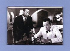 two men sitting at a table with wine bottles in front of them and one holding a glass