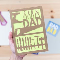 a person holding up a card with the words dad cut out on it in front of them