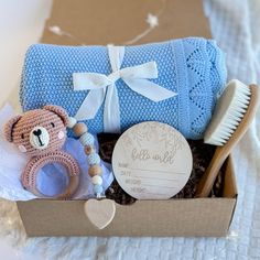 a teddy bear sitting in a box next to a baby's blanket and rattler