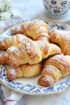 several croissants on a plate with powdered sugar