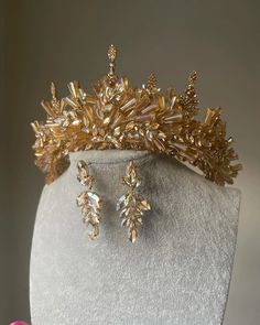 a gold tiara and earring set on a mannequin headdress