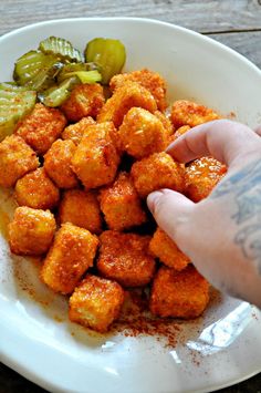 a person is reaching for some food on a white plate with peppers and jalapenos