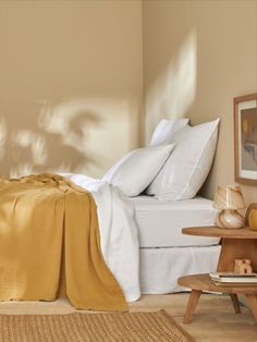 a bed with white sheets and yellow blankets