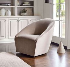 a living room with white cabinets and a beige chair