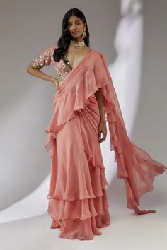 Peach pre-draped saree with ruffle detailing. Comes with embroidered padded blouse.
Component: 2
Pattern: Embroidery
Type Of Work: Floral
Neckline: Plunge V
Sleeve Type: Half
Fabric: Organza, Net, Lining: Cotton Shantoon
Color: Peach
Other Details: 
Fitted at bust and waist
Note: The neckpiece worn by the model is not for sale
Occasion: Wedding - Aza Fashions Fiji Outfits, Beach Saree, Cotton Sarees Handloom, Pretty Dresses Casual, Ruffle Sarees, Organza Embroidery, Draped Saree, Peach Saree, Ruffle Saree