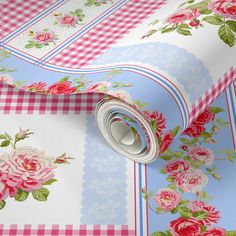 a pink and blue flowered wallpaper with roses on the border is laying next to a roll of toilet paper