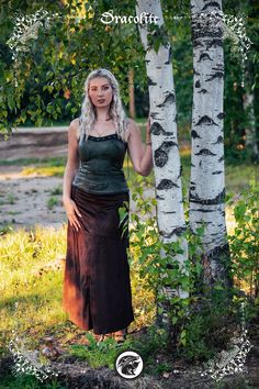 a woman standing next to a tree in the woods