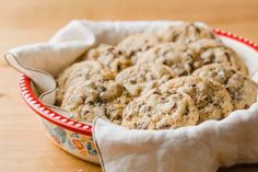 chocolate chip cookies in a red and white dish on a wooden table with a cloth