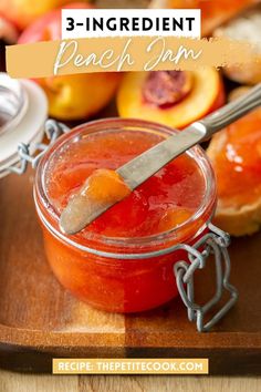 a jar filled with peach jam sitting on top of a wooden cutting board