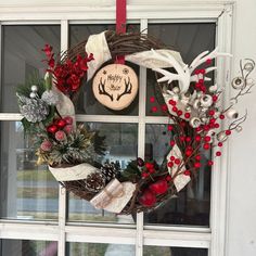 a christmas wreath with antlers and berries hanging on a window sill in front of a house