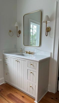 a white bathroom with two sinks and a large mirror over it's vanity area