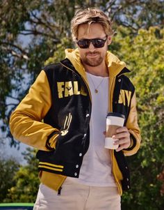 a man with sunglasses and a yellow jacket holding a cup