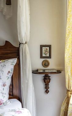 a bed sitting under a window next to a wooden table with a clock on it