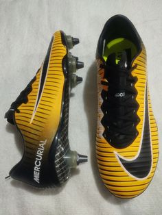 a pair of black and yellow soccer cleats on a white sheeted surface