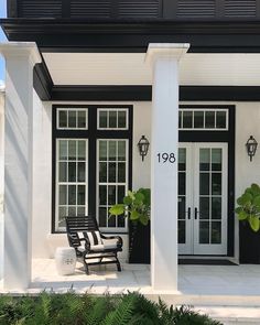 a black and white house with two chairs on the front porch