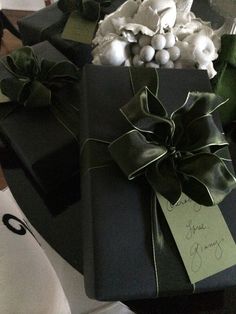 a present wrapped in black paper and tied with green ribbon, sitting on a table