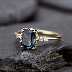 a blue and white diamond ring sitting on top of a rock