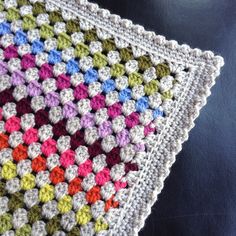 a multicolored crocheted blanket sitting on top of a black tablecloth