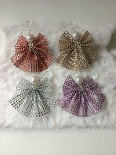 four different colored bows are hanging on a white furnishing with pearls in them