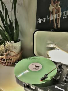 an old record player sitting on top of a table next to a plant and poster