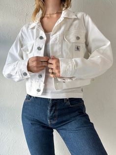 - Vintage Calvin Klein white cropped denim jacket - 100% cotton - Made in Canada - Tagged S Chest: 20" Length: 18.5" Sleeve: 23.5" We are not responsible for lost, stolen, or damaged packages once they have been shipped. Any additional customs duties or taxes incurred on international orders are the responsibility of the buyer. Please note that our items are vintage and may have minor flaws or imperfections due to their age, which adds to their unique character. White Button-up Denim Jacket For Summer, Cropped Cotton Denim Jacket For Summer, Summer Cropped Cotton Denim Jacket, Fitted Button-up Cotton Cropped Jacket, Fitted Cotton Cropped Button-up Jacket, Spring Streetwear Cropped Jacket, Fitted Cotton Cropped Jacket With Button-up, Fitted Cotton Denim Jacket For Everyday, Cropped Cotton Workwear Jacket