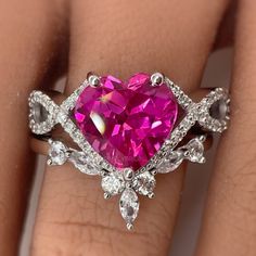 a woman's engagement ring with a pink heart shaped stone surrounded by white diamonds