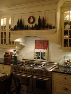 a kitchen decorated for christmas with stockings and trees on the stove top, oven hood and cabinets