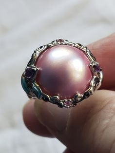 Huge pink Mabe pearl ring by Michael Valitutti. This ring also has amethyst stones and tiny sapphires. In size 8, this is a big, beautiful, heavy ring at 11.5 grams. I think he uses palladium instead of sterling silver which is a much more expensive metal that doesn't tarnish. So much shimmer! No scratches! Buy it and put it away for Christmas. They will love it! Fabulous color! I have seen these go for $189 and more... Mabe Pearl Ring, Elegant Formal Multi-stone Pearl Ring, Luxury Multi-stone Heirloom Pearl Ring, Vintage Multi-stone Pearl Ring For Formal Events, Luxury Classic Multi-stone Pearl Ring, Expensive Rings, Amethyst Stones, Mabe Pearl, Amethyst Stone