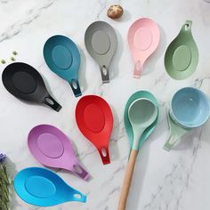 six different colored measuring spoons on a marble counter