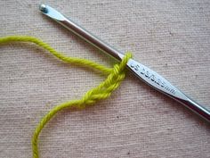 there is a crochet hook with yellow yarn next to it