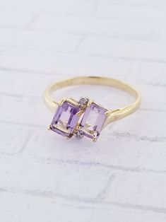 Amethyst & Diamond ring. This ring features two emerald cut Amethyst stones with a small diamond on top and bottom. Details: Size: US 6 1/4 ( Can be sized ) Weight: 1.5 grams Primary stone: Amethyst Stone Shape: Emerald Cut ( Appx. 6mm x 4mm ) Secondary Stone: Diamond Stone Shape: Round Metal: 10k Yellow Gold Condition: Brand new Inside of band is stamped and tested for '10k' gold. SIZING: Currently this ring is a size 6 1/4 but could be sized up or down for an additional small fee if desire Emerald Cut Amethyst Ring With Gemstone Accents For Formal, Emerald-cut Amethyst Ring With Gemstone Accents For Formal, Emerald Cut Amethyst Ring With Gemstone Accents, Anniversary Amethyst Ring With Rectangular Stone, Fine Jewelry Amethyst Ring For Anniversary, Emerald Cut, Fine Jewelry Emerald Cut Amethyst Ring For Anniversary, Emerald Cut Amethyst Ring In Yellow Gold, Octagon Amethyst Ring For Anniversary, Octagonal Amethyst Anniversary Ring In Fine Jewelry Style