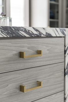 a close up of a drawer with marbled drawers and brass pulls on it's handles