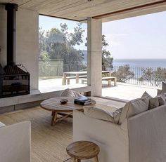 a living room with couches, tables and a fire place in front of an ocean view