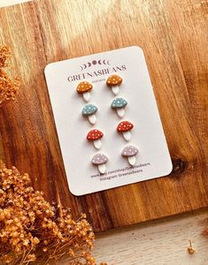 two pairs of mushroom earrings on a wooden surface