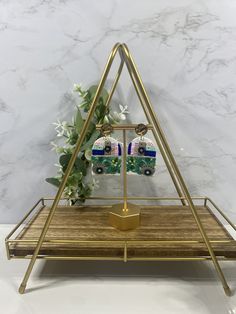 the triangle shaped earrings are on display in front of a marble wall and gold stand