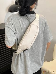 the back of a woman wearing a white sling backpack