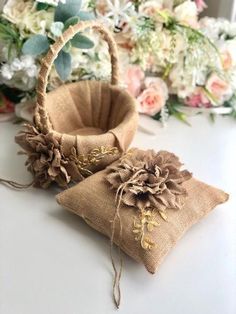 two small bags with flowers on them sitting on a table next to some flowers and greenery