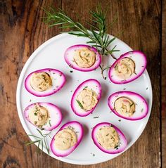 deviled eggs on a white plate topped with hummus and dill garnish