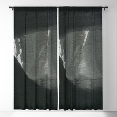 black and white photograph of two curtains in front of a wall with an abstract painting on it