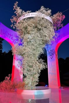 a tall white tree sitting in the middle of a park at night with graffiti on it's walls