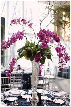 a vase filled with purple flowers sitting on top of a black table cloth covered table