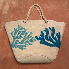 a white bag with blue corals on the side and rope handles hanging from it