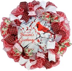 a red and white christmas wreath with a cardinal bird on the front, surrounded by bows