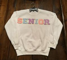 Cute senior sweatshirt with letter patches! Offer different color sweatshirts and does't have to say senior! White Letter Patch Top For College, White Top With Letter Patch For College, White College Top With Letter Patch, College Spring Sweatshirt With Letter Embroidery, Spring College Sweatshirt With Letter Embroidery, White Letter Embroidery Sweatshirt For School, School Fleece Sweatshirt With Letter Print, White Crew Neck Sweatshirt With Letter Patch, Casual School Sweater With Letter Print