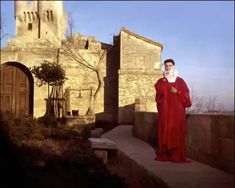 a woman in a red dress is standing outside